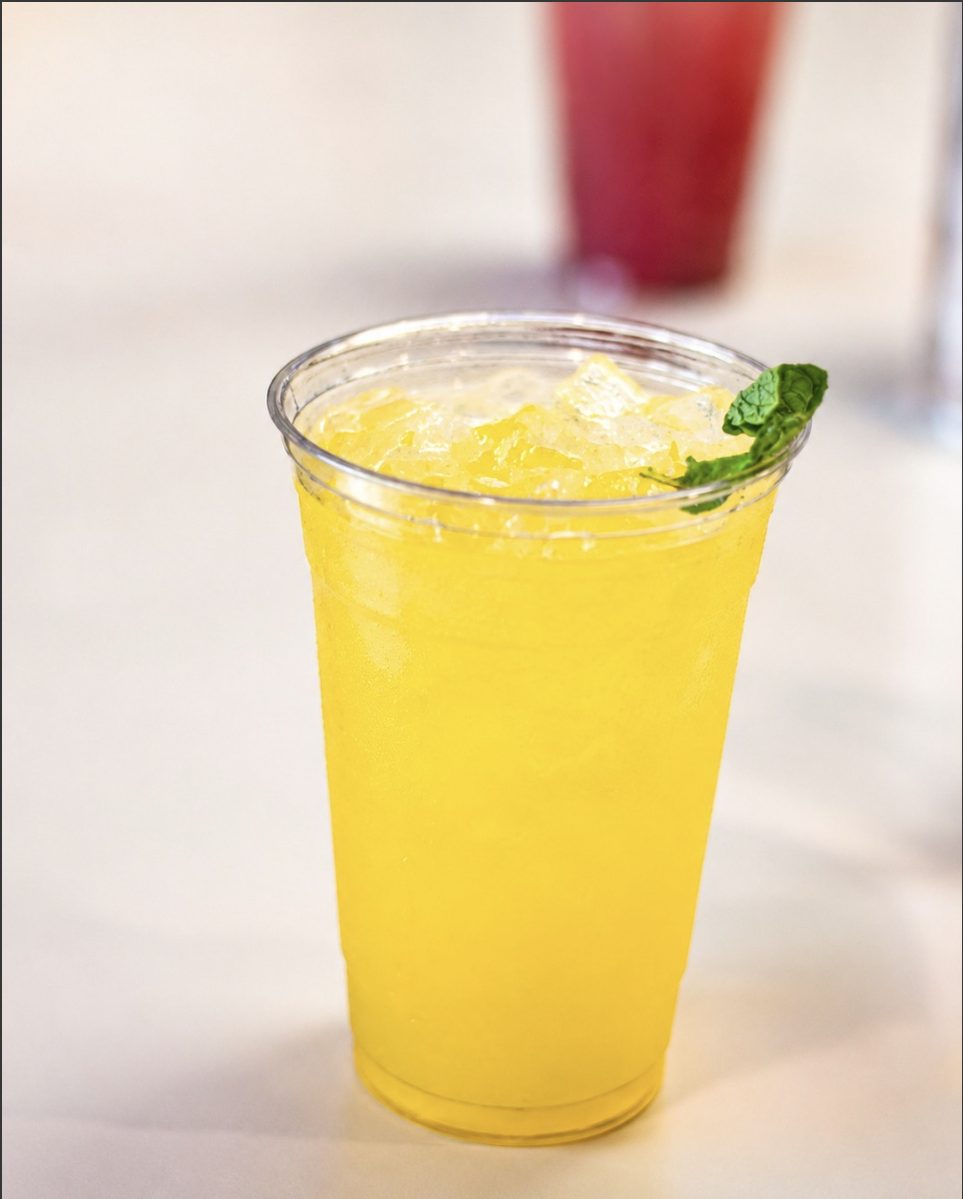 A bright yellow iced mocktail over crushed ice, garnished with mint.